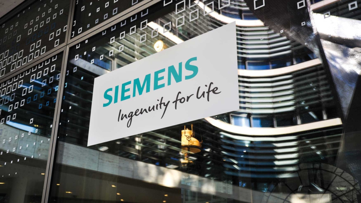 Siemens logo displayed on a glass building facade with modern architecture reflected behind it.