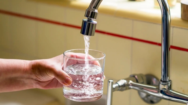 Glass of drinking water being filled from a household tap